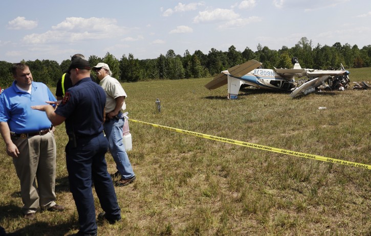 Investigators stand next to the debris of a plane crash at West Georgia Regional Airport in Carrollton, Ga., Wednesday, Sept. 7, 2016. Carroll County Fire Chief Scott Blue says two single-engine planes may have been trying to land at the same time when they collided at the small airport in western Georgia leaving three people dead. (AP Photo/David Goldman)