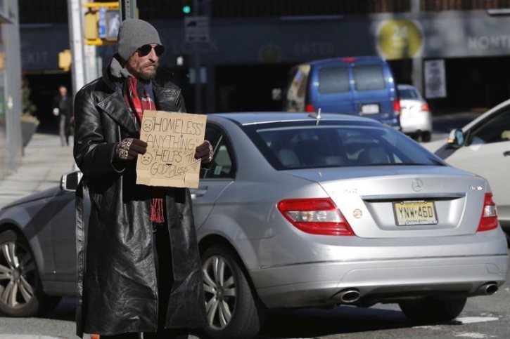 FILE - A car drives past a homeless man as he panhandles on the street in New York, January 4, 2016.  Reuters