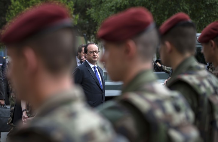 FILE - In this July 25, 2016 file photo, French president Francois Hollande reviews troops at the army base and command centre for France's anti-terror 'Vigipirate' plan, dubbed 'Operation Sentinelle', in Vincennes, outside Paris. France's government has approved Wednesday Oct. 12, 2016 a decree creating a National Guard to bolster security against extremist attacks across the country. The Guard, which is expected to reach 84,000 people by 2018, is a new, enhanced version of the existing reserve forces. (Ian Langsdon/Pool Photo via AP, File)