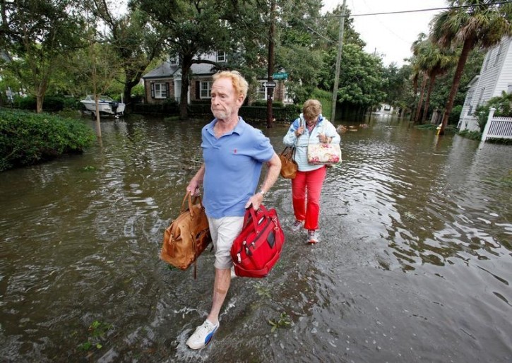Residents of an upscale historic neighborhood wade through flood waters as they return to their home after Hurricane Matthew hit Charleston, South Carolina October 8, 2016.   REUTERS/Jonathan Drake 