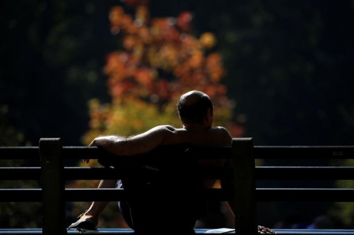 A man sits on a bench during warm weather in Central Park in New York City, U.S., October 18, 2016. REUTERS/Shannon Stapleton 