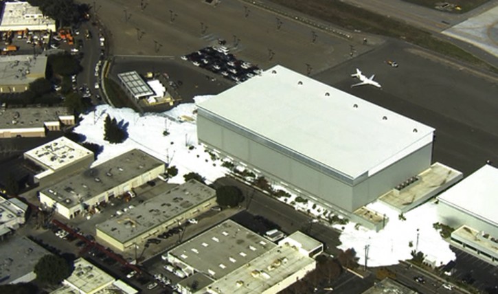 In this image provided courtesy of KTVU-TV, foam spills out of a hanger building at the Mineta San Jose International Airport, Friday, Nov. 18, 2016, in San Jose, Calif. The San Jose fire department said a malfunction of the new hangar's fire prevention system caused the flooding foam. (Courtesy of KTVU-TV via AP)