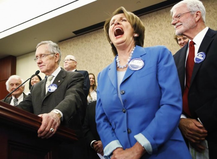 FILE - U.S. House Minority Leader Nancy Pelosi (R) laughs as Senate Majority Leader Harry Reid (L) makes a joke about Republican opposition to federal health plans at a rally to celebrate the start of the Affordable Care Act (commonly known as Obamacare) at the U.S. Capitol in Washington, October 1, 2013.  Reuters