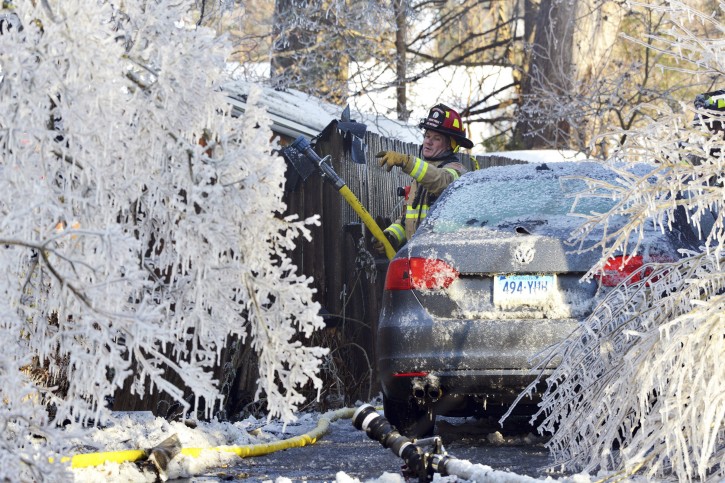 FILE- In this Jan. 5, 2018 file photo, afirefighter from the Longmeadow Fire Department battles a house fire in Longmeadow, Mass. Firefighters battling blazes in the extreme cold are faced with treacherous conditions, frozen hydrants and slick surfaces that make an already difficult job even harder. Departments in colder climates prepare months ahead for the coming freeze, readying equipment and changing how they approach fires in the coldest months. (Dave Roback/The Republican via AP)