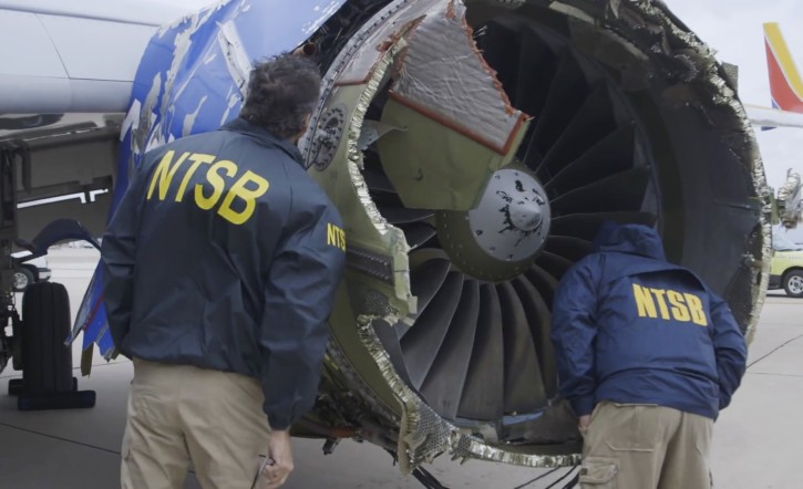 In this Tuesday, April 17, 2018 frame from video, a National Transportation Safety Board investigator examines damage to the engine of the Southwest Airlines plane that made an emergency landing at Philadelphia International Airport in Philadelphia.  (NTSB via AP)