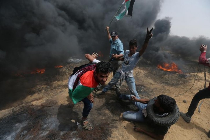 Demonstrators take cover during clashes with Israeli troops at a protest where Palestinians demand the right to return to their homeland, at the Israel-Gaza border in the southern Gaza Strip, April 20, 2018. REUTERS/Ibraheem Abu Mustafa 