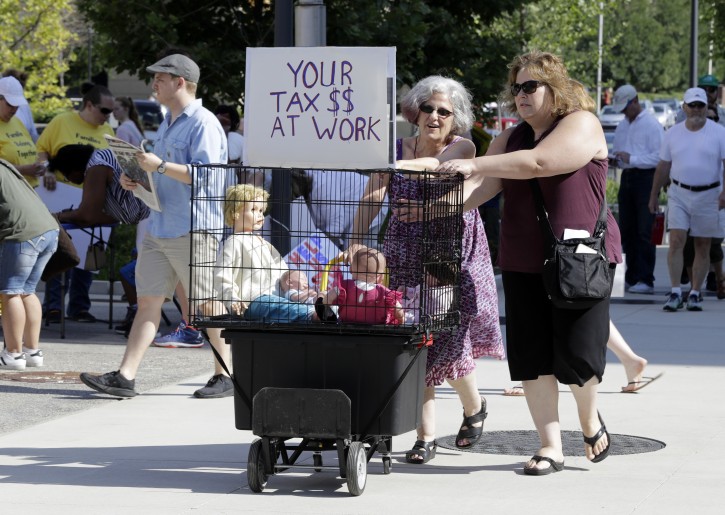Deborah Langerman and Cara Hwang push a cart to a protest of the Trump administration's approach to illegal border crossings and separation of children from immigrant parents at the Statehouse, Saturday, June 30, 2018, in Indianapolis. (AP Photo/Darron Cummings)