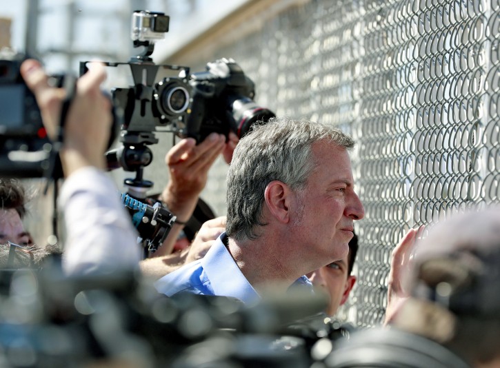 New York City Mayor Bill de Blasio looks through a closed gate at the Port of Entry facility, Thursday, June 21, 2018, in Fabens, TX., where tent shelters are being used to house separated family members. (AP Photo/Matt York)