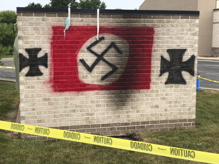 A garbage shed spray painted by vandals with a Nazi flag and iron crosses stands on the grounds of the Congregation Shaarey Tefilla synagogue in Carmel, Ind., outside Indianapolis, on Monday, July 30, 2018. Republican Indiana Gov. Eric Holcomb is calling on the General Assembly to pass a hate crimes bill after someone spray-painted anti-Semitic graffiti at the suburban Indianapolis synagogue. (Justin Mack/The Indianapolis Star via AP)