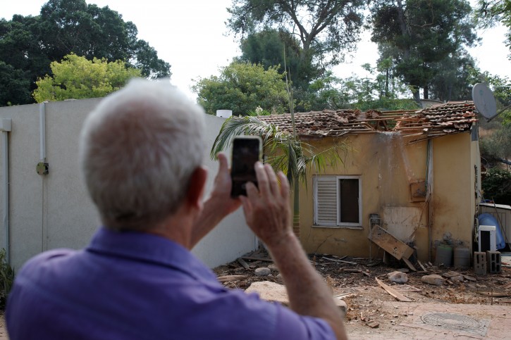 An Israeli man takes pictures with his phone next to the scene where a rocket exploded in the southern Kibbutz of Yad Mordechai, Israel August 9, 2018. REUTERS/Amir Cohen