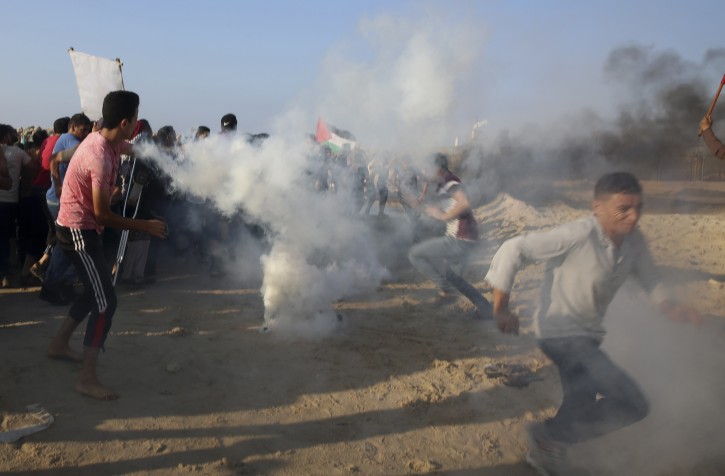 Protesters run from teargas fired by Israeli soldiers during a protest on the beach at the border with Israel near Beit Lahiya, northern Gaza Strip, Monday, Sept. 17, 2018. (AP Photo/Adel Hana)
