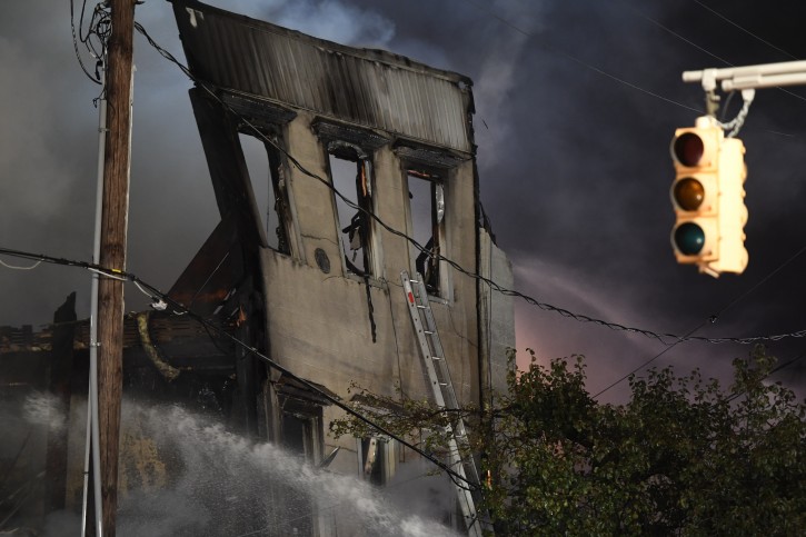 Part of the building that collapsed can be seen through the smoke as first responders fight a seven-alarm fire on Monday, Oct. 22, 2018 in Dover, N.J. The fast-moving blaze ripped through the business district, destroying multiple businesses and causing the partial collapse of at least four buildings, according to officials. (Danielle Parhizkaran/The Record via AP)
