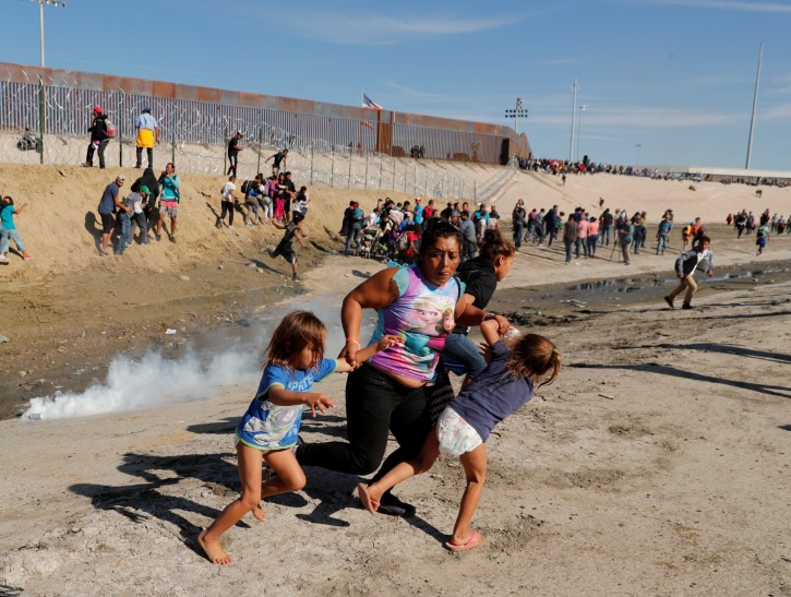 Maria Lila Meza Castro (C), a 39-year-old migrant woman from Honduras, part of a caravan of thousands from Central America trying to reach the United States, runs away from tear gas with her five-year-old twin daughters Saira Nalleli Mejia Meza (L) and Cheili Nalleli Mejia Meza (R) in front of the border wall between the U.S. and Mexico, in Tijuana, Mexico, November 25, 2018. REUTERS/Kim Kyung-Hoon/File photo