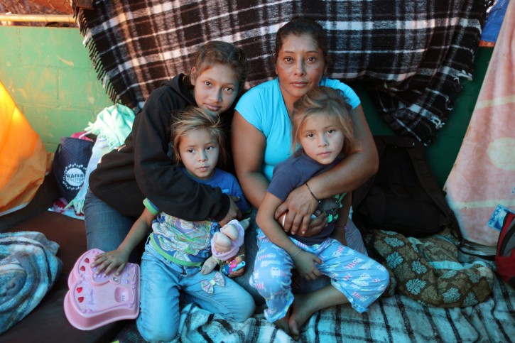 Maria Lila Meza Castro (back R) a 39-year-old migrant woman from Honduras, who is part of a caravan of thousands from Central America trying to reach the United States, sits with her daughter Jamie Jisel Mejia Meza, 13, (back L) and her 5-year-old twin daughters, Cheili Nalleli Mejia Meza and Saira Nalleli Mejia Meza in her tent in a temporary shelter in Tijuana, Mexico, November 26, 2018. The family was depicted in a Reuters photo of November 25 running away from tear gas. REUTERS/Lucy Nicholson