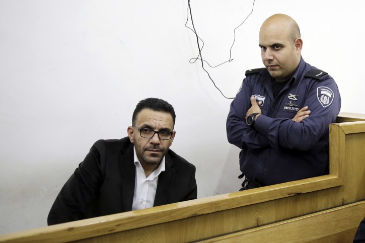 In this Thursday, Nov. 29, 2018 photo, Israeli policeman watches over a Palestinian governor of Jerusalem Adnan Ghatith during a court appearance following his arrest in Jerusalem. AP