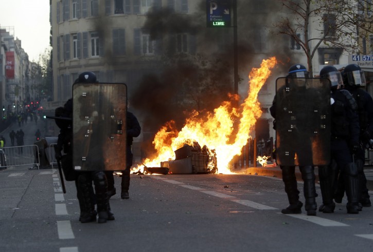 Riot police officer stand in front a burning trash bin during clashes, Saturday, Dec. 8, 2018 in Marseille, southern France. French riot police fired tear gas and water cannon in Paris on Saturday, trying to stop thousands of yellow-vested protesters from converging on the presidential palace to express their anger at high taxes and French President Emmanuel Macron. (AP Photo/Claude Paris)