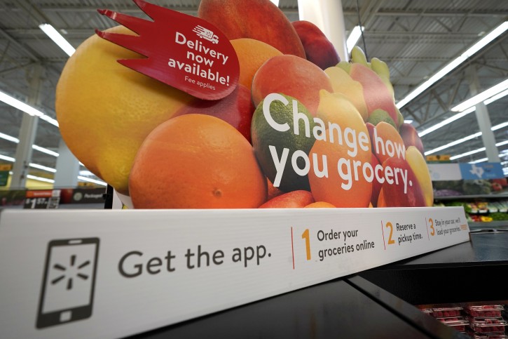FILE - In this Nov. 9, 2018, file photo a sign promotes online and home delivery of groceries at a Walmart Supercenter  in Houston. Retailers are taking back some control of the store experience with smart phone app features that let customers do things like scan and pay and download digital maps. (AP Photo/David J. Phillip, File)