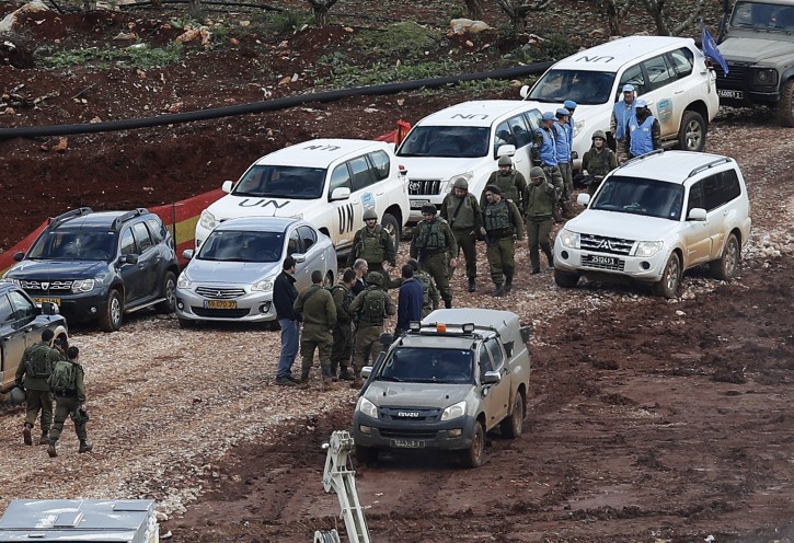 In this Thursday, Dec. 13, 2018 photo, Israeli soldiers and UN peacekeepers gather at the site where the Israeli army works on the Lebanese-Israeli border in the southern village of Kafr Kila, Lebanon. AP