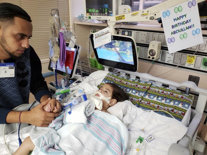This recent but undated photo, released Monday, Dec. 17, 2018 by the Council on American-Islamic Relations in Sacramento, Calif., shows Ali Hassan with his dying 2-year-old son Abdullah in a Sacramento hospital.(Council on American-Islamic Relations via AP)