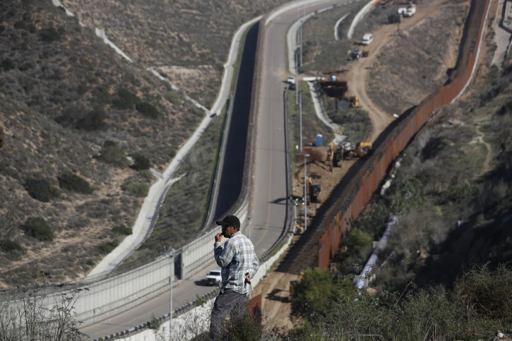 A man looks out at the U.S. border where workers are replacing parts of the U.S. border wall for a higher one, in Tijuana, Mexico, Wednesday, Dec. 19, 2018. Workers are reinforcing and changing pieces of the wall where migrants seeking to reach the U.S. have been crossing. (AP Photo/Moises Castillo)