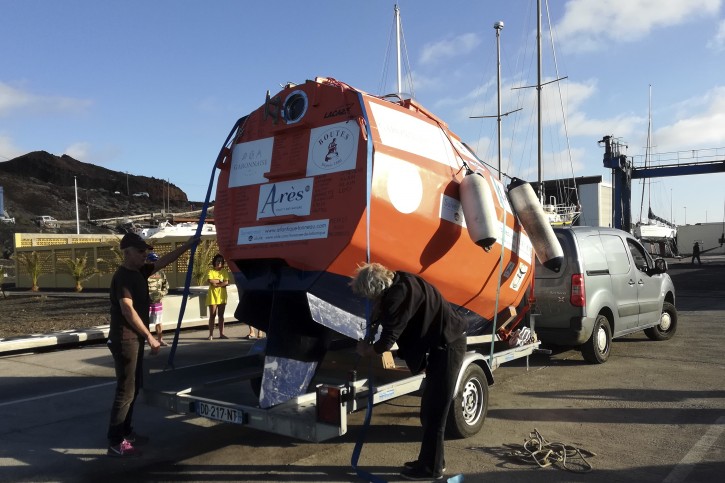 In this photograph taken Saturday Dec. 22, 2018, Frenchman Jean-Jacques Savin, 71-year-old, left, unloads his 3-metre (10-foot) long, 2.1-metre (7-foot) wide resin-coated plywood capsule, which will use ocean currents alone to propel him across the sea. Savin set off from El Hierro in Spain's Canary Islands on Wednesday and is aiming to complete his 4,500-kilometre (2,800-mile) journey to the Caribbean in about three months. (Courtesy of Jean-Jacques Savin via AP)