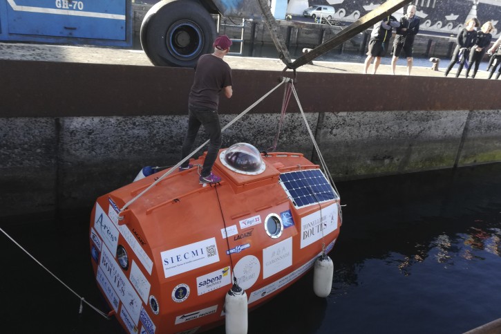 In this photograph taken Saturday Dec. 22, 2018, Frenchman Jean-Jacques Savin, 71-year-old, stands ontop of his 3-metre (10-foot) long, 2.1-metre (7-foot) wide resin-coated plywood capsule, which will use ocean currents alone to propel him across the sea. Savin set off from El Hierro in Spain's Canary Islands on Wednesday and is aiming to complete his 4,500-kilometre (2,800-mile) journey to the Caribbean in about three months. (Courtesy of Jean-Jacques Savin via AP)