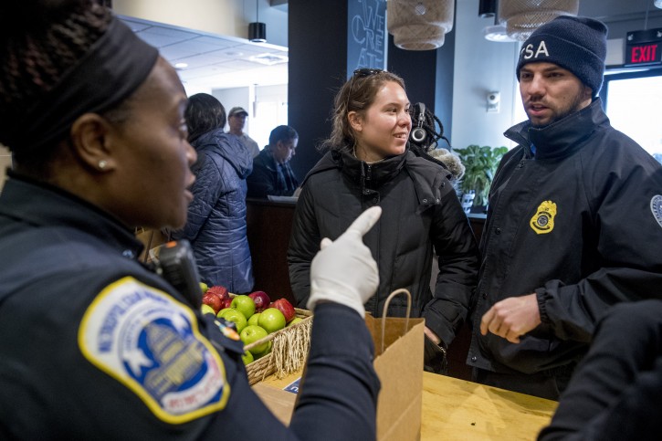Metropolitan Police Officer and volunteer Adriane Benson, left, takes a food order for Shane Smith, a TSA agent, right, as he and other furloughed government workers affected by the shutdown receive free food and supplies at World Central Kitchen, the not-for-profit organization started by Chef Jose Andres, Tuesday, Jan. 22, 2019 in Washington.  (AP Photo/Andrew Harnik)