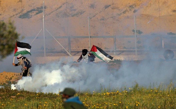 Women holding Palestinian flags run away from tear gas fired by Israeli forces during a protest at the Israel-Gaza border fence, in the southern Gaza Strip February 8, 2019. REUTERS/Ibraheem Abu Mustafa