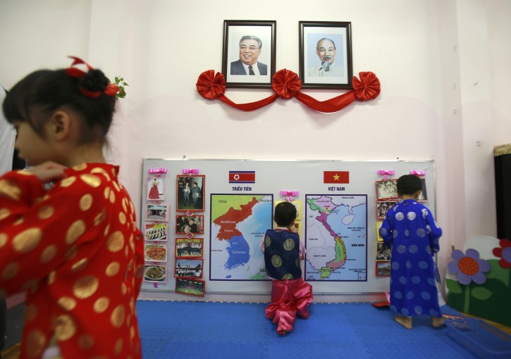 In this Feb.21, 2019, photo, children, in Vietnamese and Korean traditional costumes, stick photos on Vietnamese and Korean maps at Vietnam-North Korea friendship kindergarten in Hanoi, Vietnam. The children have been practicing singing and dancing, hoping to show off their talents to North Korean leader Kim Jong Un when he comes to town this week for his second summit meeting with U.S. President Donald Trump. (AP Photo/ Hau Dinh)