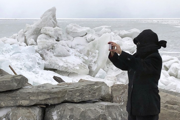 Rose Hirschbeck, of Hamburg, NY, photographs mounds of ice collected along the Lake Erie shore at Hoover Beach, in Hamburg, N.Y., Monday, Feb. 25, 2019. High winds howled through much of the nation's eastern half for a second day Monday, cutting power to hundreds of thousands of homes and businesses, closing schools, and pushing dramatic mountains of ice onto the shores of Lake Erie. (AP Photo/Carolyn Thompson)