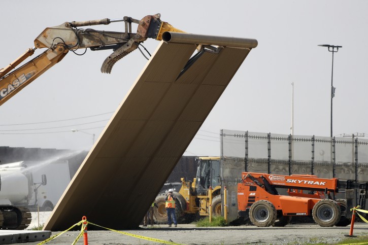 A border wall prototype falls during demolition at the border between Tijuana, Mexico, and San Diego, Wednesday, Feb. 27, 2019, in San Diego. The government is demolishing eight prototypes of Donald Trump's prized border wall that instantly became powerful symbols of his presidency when they were built nine months after he took office. (AP Photo/Gregory Bull)