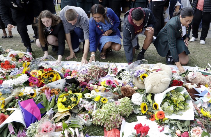 Students from Christchurch high schools light candles at a floral tribute at the Botanical Gardens in Christchurch, New Zealand, Tuesday, March 19, 2019. Christchurch was beginning to return to a semblance of normalcy Tuesday. Streets near the hospital that had been closed for four days reopened to traffic as relatives and friends of Friday's shooting victims continued to stream in from around the world. (AP Photo/Mark Baker)