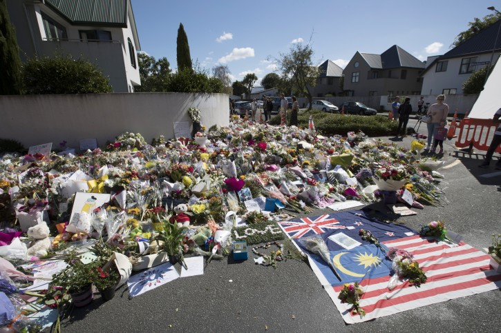 Mourners lay flowers on a wall outside the Al Noor mosque in Christchurch, New Zealand, Monday, March 18, 2019. Four days after Friday's attack, New Zealand's deadliest shooting in modern history, relatives were anxiously waiting for word on when they can bury their loved ones. (AP Photo/Vincent Thian)