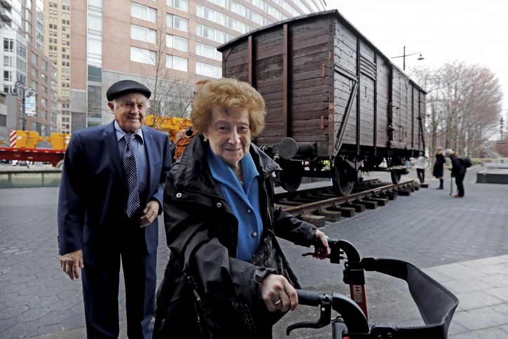 Holocaust survivors Leon Kaner, age 94, and his wife Ray Kaner, age 92, pass a vintage German train car, like those used to transport people to Auschwitz and other death camps, outside the Museum of Jewish Heritage, in New York, Sunday, March 31, 2019. The train car joins hundreds of artifacts from Auschwitz at the museum for an exhibit entitled "Auschwitz. Not long ago. Not far away," that opens to the public on May 8. (AP Photo/Richard Drew)