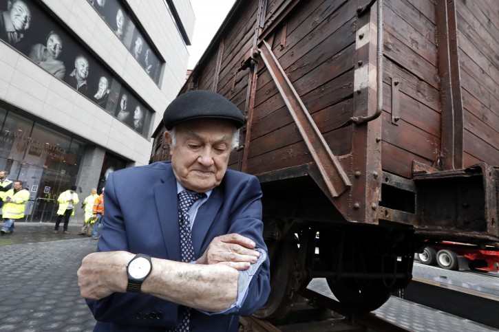 Holocaust survivor Leon Kaner, age 94, shows his tattoo number as he stands beside a vintage German train car, like those used to transport people to Auschwitz and other death camps, outside the Museum of Jewish Heritage, in New York, Sunday, March 31, 2019