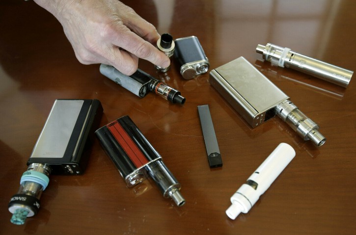 FILE - In this April 10, 2018, file photo, a high school principal displays vaping devices that were confiscated from students in such places as restrooms or hallways at the school in Massachusetts. On Wednesday, April 3, 2019, the U.S. Food and Drug Administration said it has not established a direct connection between vaping and seizures but is seeking more information. Regulators noted that seizures and convulsions are a known side effect of nicotine poisoning. (AP Photo/Steven Senne, File)