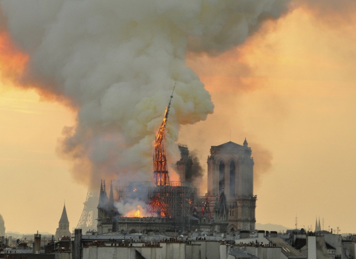 In this image made available on Tuesday April 16, 2019 flames and smoke rise from the blaze as the spire starts to topple on Notre Dame cathedral in Paris, Monday, April 15, 2019. (AP Photo/Thierry Mallet)