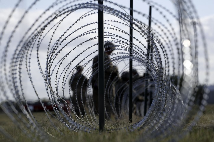FILE--In this Nov. 3, 2018, file photo, members of the U.S. Army build a razor wire fence around area for tents near the U.S.-Mexico International bridge, in Donna, Texas. (AP Photo/Eric Gay, File)