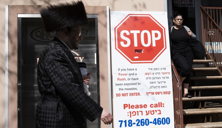 FILE - People walk past a sign outside of health clinic with warnings about measles in the Jewish area of  the Williamsburg neighborhood in Brooklyn, New York, USA, 25 April 2019.EPA