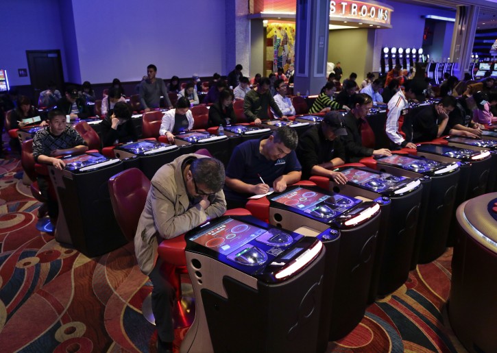 FILE - In this Oct. 3, 2014, file photo, visitors to the Resorts World Casino at the Aqueduct racetrack play electronic baccarat games, in the Queens borough of New York.Former New York Gov. David Paterson is joining Las Vegas Sands to lead the casino and resort developer's push to build a casino in New York City. Up to three casino licenses are available, though a state law bans casinos in the city until 2023. (AP Photo/Julie Jacobson, File)
